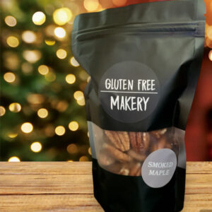 One single bag of pecans from the Gluten Free Makery sitting on a wooden table in front of a Christmas tree.